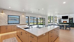 A modern kitchen with a large island, built-in appliances, and a view of the outdoors.