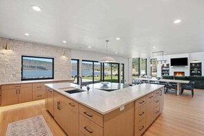 A modern kitchen with a large island, built-in appliances, and a view of the outdoors.