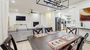 A modern kitchen with white cabinets, a stainless steel refrigerator, and a dining area with a wooden table and chairs. - Balcony & Pool Access! Extended Stay in Scottsdale (Scottsdale)