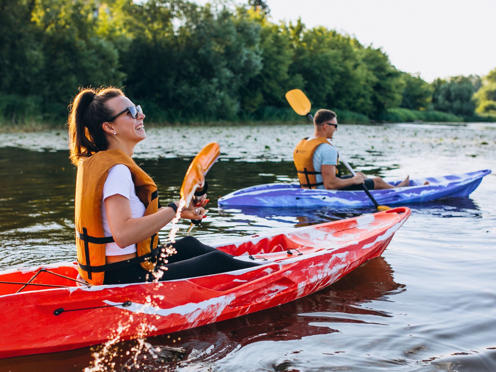 Dos personas haciendo kayak en un río tranquilo.
