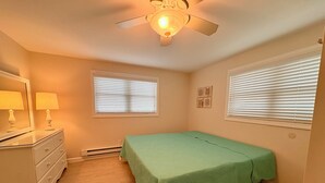 Ein Schlafzimmer mit Bett, Kommode und Deckenventilator.