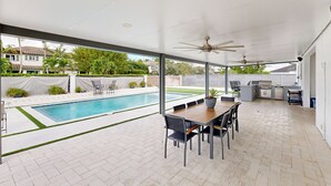 A covered outdoor area with a pool, a dining table with chairs, ceiling fans, and a kitchen area. - Outdoor Oasis! Group-Friendly Miami Getaway (Miami)