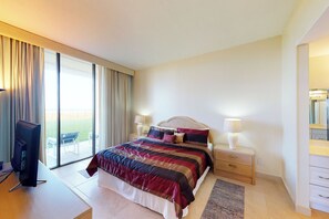 A hotel room with a large bed, a TV, a desk, and a sliding glass door to the outside. - Gulf-View 3BR, Patio, Yard: Suntide III - Unit 101 (South Padre Island)