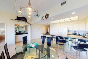 A modern kitchen with white cabinets, a dining area with a glass table and chairs, and a ceiling with a ship's wheel decoration. - Gulf-View 3BR, Patio, Yard: Suntide III - Unit 101 (South Padre Island)