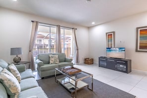 A living room with a sofa, a glass coffee table, a TV, and a cabinet. - 1521 Dream (Clermont)