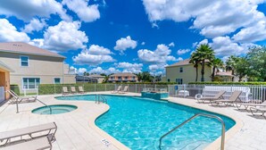 A swimming pool with lounge chairs and a deck, surrounded by buildings and palm trees. - 17517 Dream (Clermont)