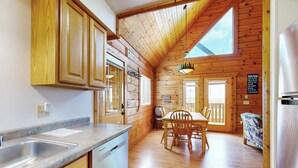 A wooden cabin interior with a kitchen, dining area, and a large window. - Steps to Three Bears Resort! Outdoorsy Escape (Warrens)
