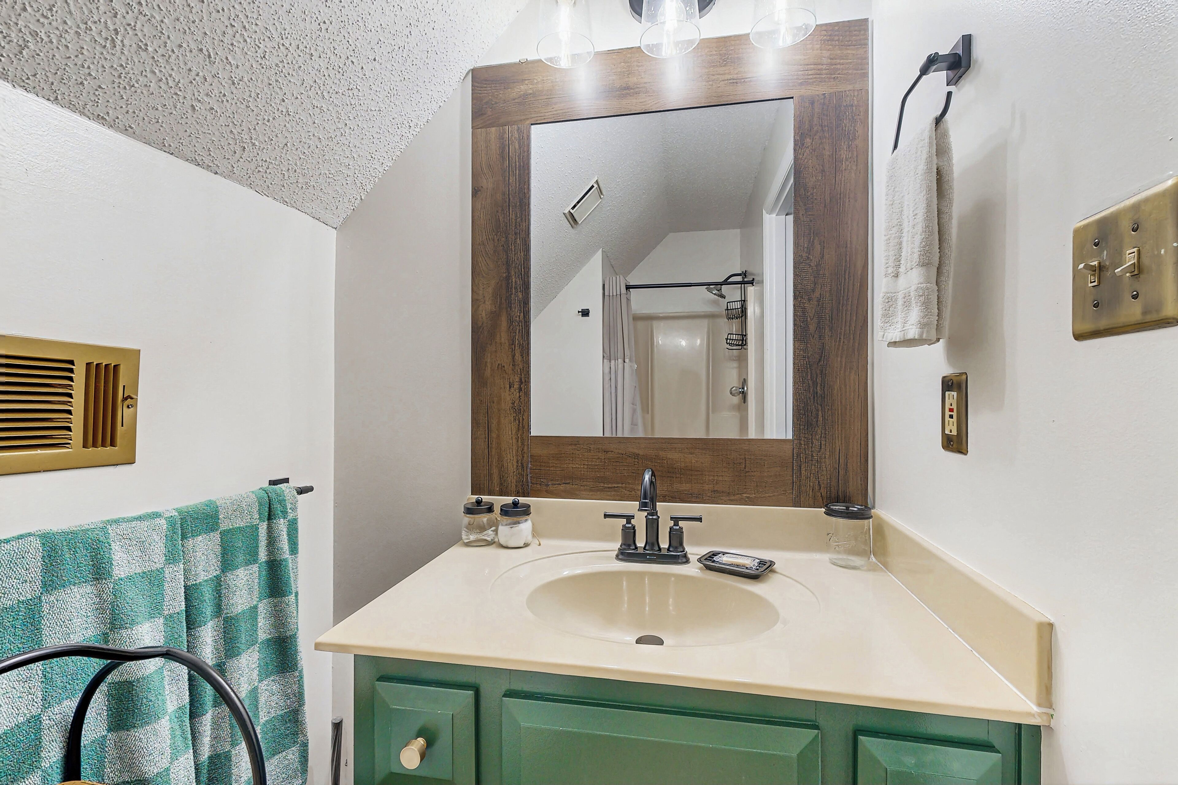 A bathroom with a sink, mirror, and green cabinets.
