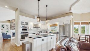 A spacious kitchen with white cabinetry, a central island, stainless steel appliances, and pendant lighting. - Patio & On-Site Fishing! Plummer Lake Escape (Centralia)