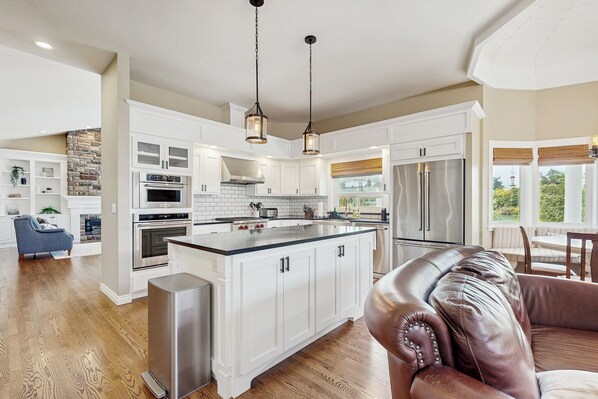 A spacious kitchen with white cabinetry, a central island, stainless steel appliances, and pendant lighting. - Patio & On-Site Fishing! Plummer Lake Escape (Centralia)