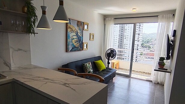 A modern kitchen with a marble countertop, pendant lights, and a dining area with a sofa and a fan. - Apartment in Cartagena Torices near the sea of Marbella (Cartagena de Indias)