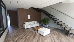 A modern living room with a white sofa, a coffee table, and a staircase with glass railings. - Apartment in Cartagena Torices near the sea of Marbella (Cartagena de Indias)