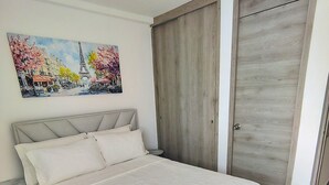 A bedroom with a bed, a door, and a painting on the wall. - Apartment in Cartagena Torices near the sea of Marbella (Cartagena de Indias)