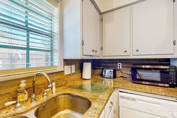 A kitchen with a stainless steel sink, a microwave, a toaster, and white cabinets. - Poolside Bliss! Christian Pass Family Home w/ Yard (Pass Christian)