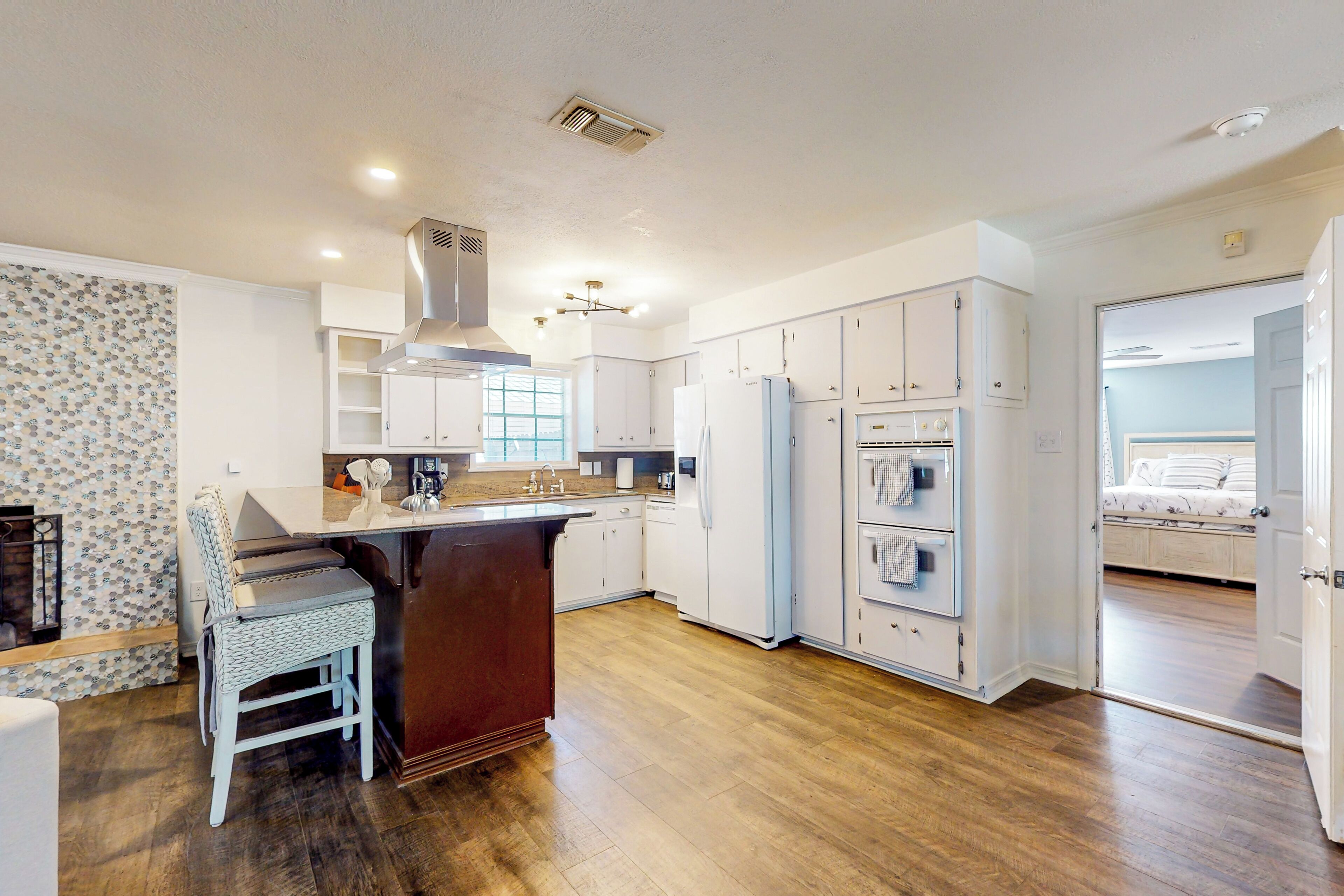A kitchen with white cabinets, a wooden floor, and a built-in island with seating.
