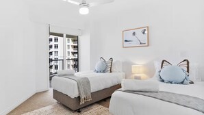 Une chambre moderne avec deux lits, une grande fenêtre et une vue sur la ville.