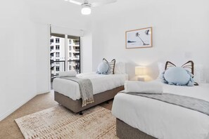 A modern bedroom with two beds, a large window, and a city view. - Large 3 Bedroom Ocean Views (Surfers Paradise)