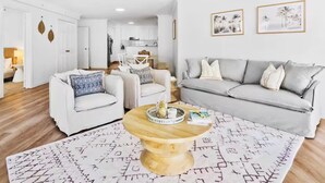 Un salon moderne avec un canapé gris, un fauteuil blanc et une table basse sur laquelle se trouve un plateau.