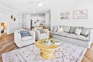 A modern living room with a grey sofa, a white armchair, and a coffee table with a tray. - Large 3 Bedroom Ocean Views (Surfers Paradise)