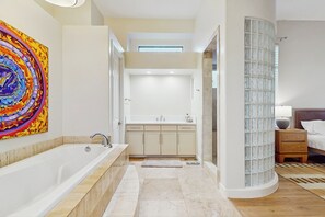 Une salle de bain moderne dotée d’une grande baignoire, d’une cabine de douche en verre et d’une douche à l’italienne.