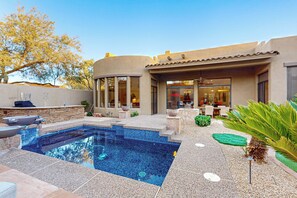 Une maison moderne dotée d’une piscine, d’un espace salon extérieur et d’un patio.