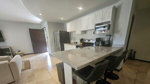 A modern kitchen with a large island, white cabinets, and a stainless steel refrigerator. - Main floor, Family unit, 3 bed, fresh, clean, inside Tamarindo w incredible pool (Tamarindo)