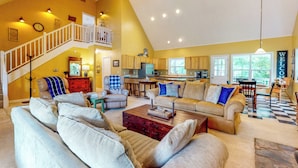 A spacious living room with a high ceiling, a staircase, and a kitchen in the background. - Creekside Seclusion: 'HomeSted Retreat' in Dallas (Dallas)