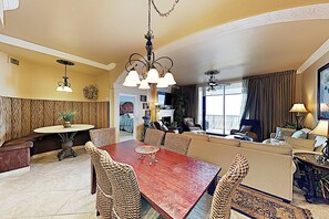 Ein Essbereich mit Holztisch und Korbstühlen, einer Chandelier und Blick auf das Wohnzimmer.
