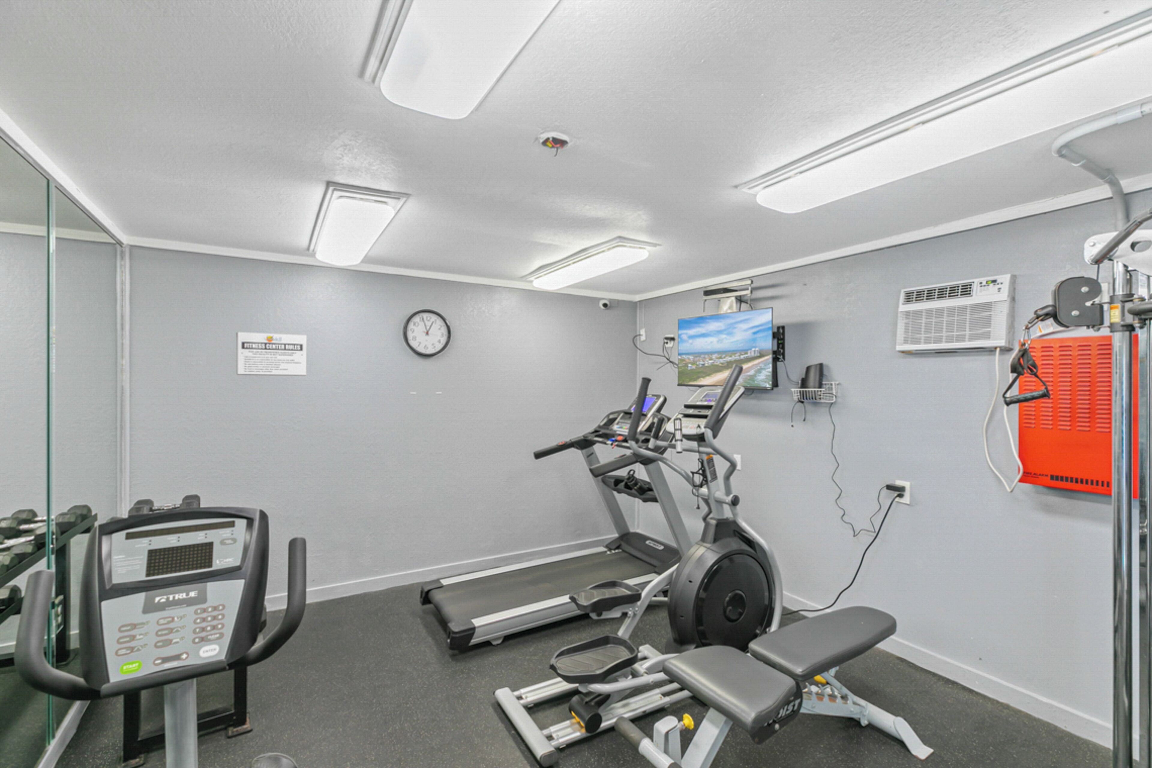 Ein Fitnessraum mit Laufbändern, einem Crosstrainer und einer Bank.