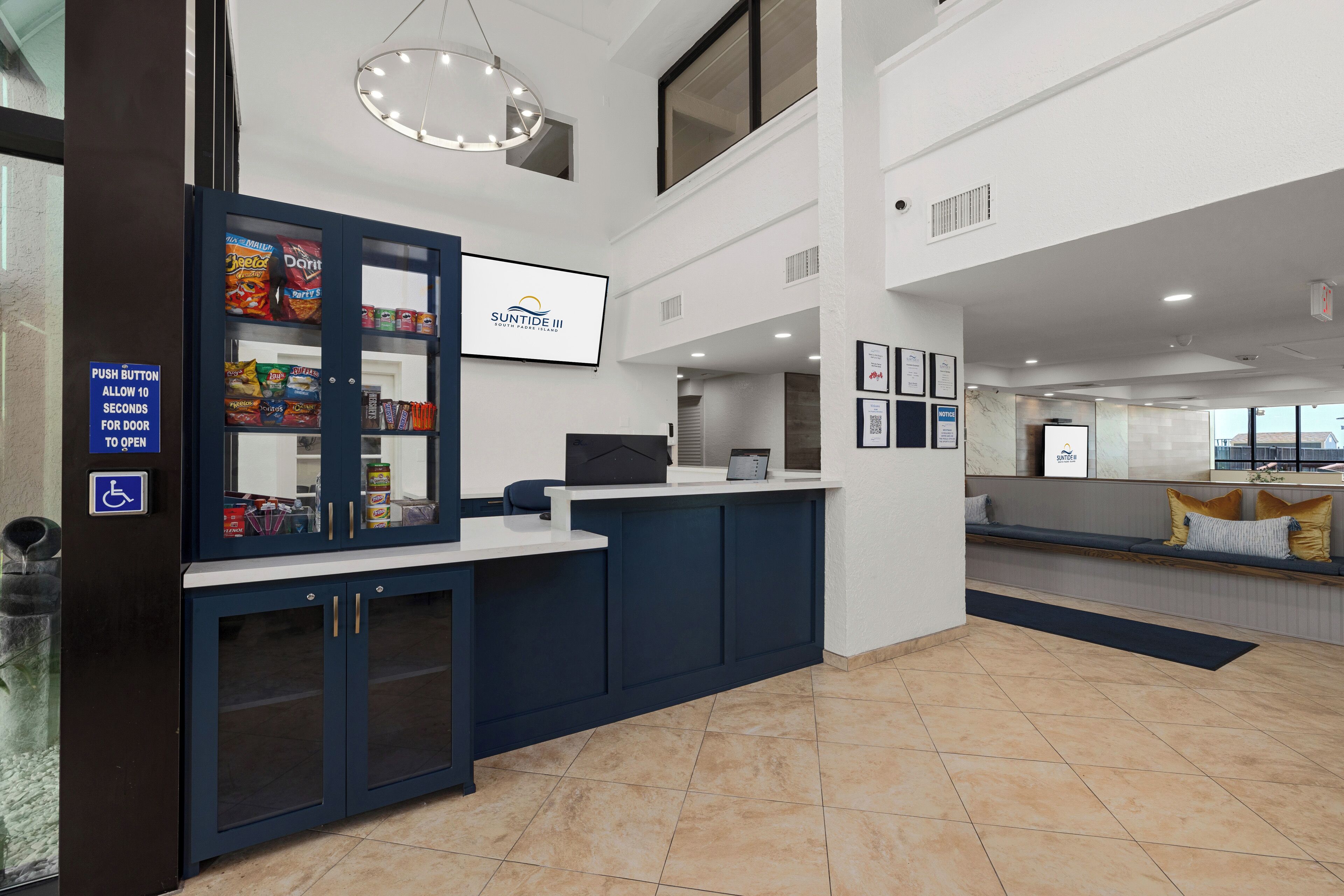 A reception area with a counter, a vending machine, a seating area, and a sign indicating a push button for the door.