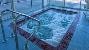 Un jacuzzi con barandilla metálica y borde de azulejos rojos.