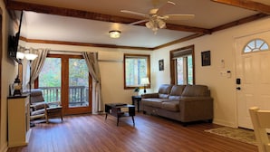 A spacious living room with hardwood floors, a ceiling fan, and a large window. - Cozy A frame cabin in quaint Front Royal. Dog friendly (Front Royal)