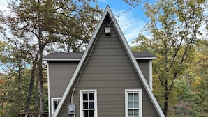 A two-story house with a steeply pitched roof, a front porch, and a driveway. - Cozy A frame cabin in quaint Front Royal. Dog friendly (Front Royal)