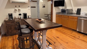A kitchen with a wooden table, bar stools, a coffee maker, a microwave, and a dishwasher. - Cozy A frame cabin in quaint Front Royal. Dog friendly (Front Royal)