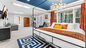 A modern bedroom with a bed, a desk, a chair, and a large window with curtains. - KnoxHaven | 5 Min UT•Hot Tub•Firepit•Theater•Games (Knoxville)