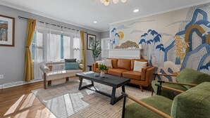 A living room with a sofa, a coffee table, and a green armchair. - KnoxHaven | 5 Min UT•Hot Tub•Firepit•Theater•Games (Knoxville)