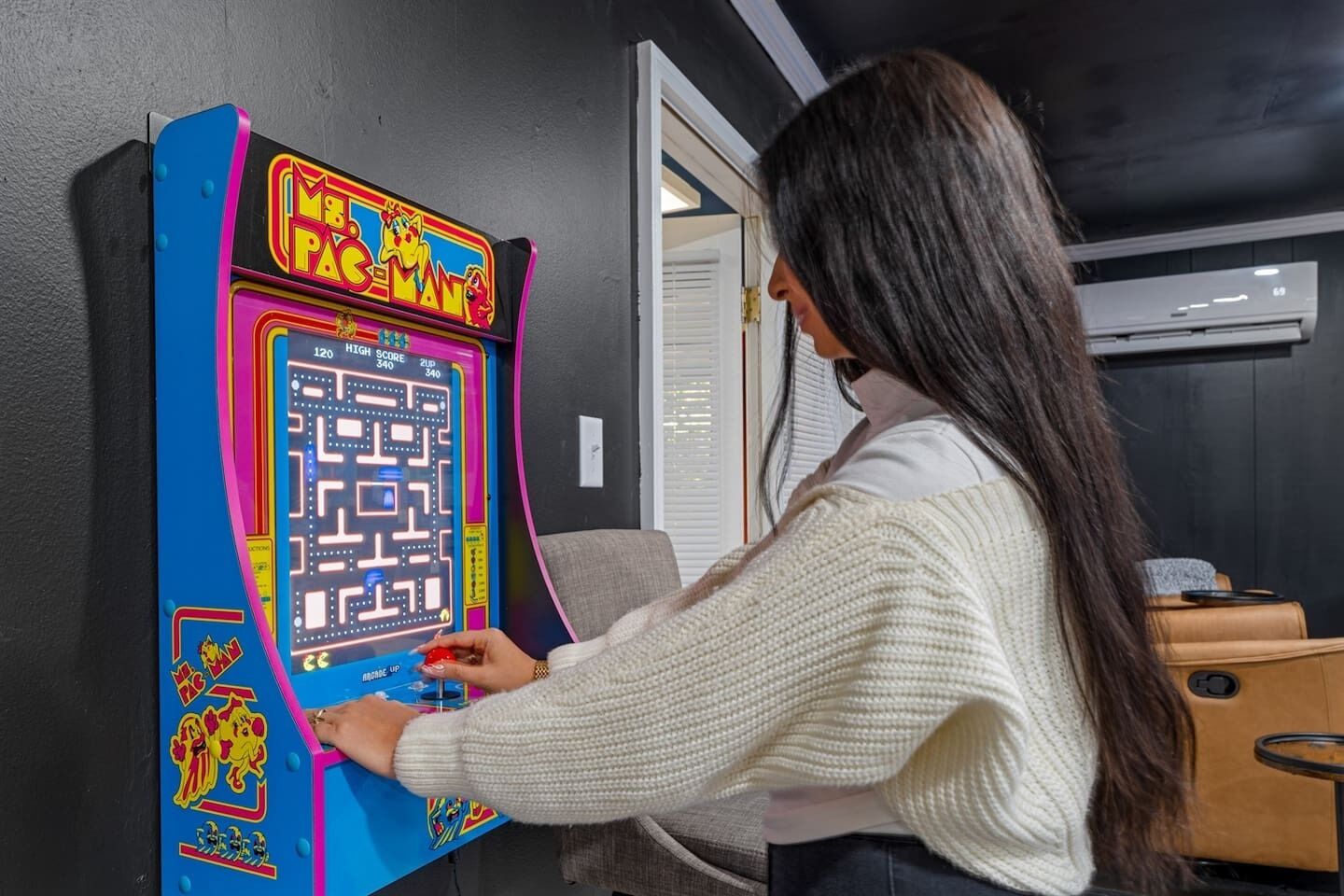 A person playing a Pac-Man arcade game.