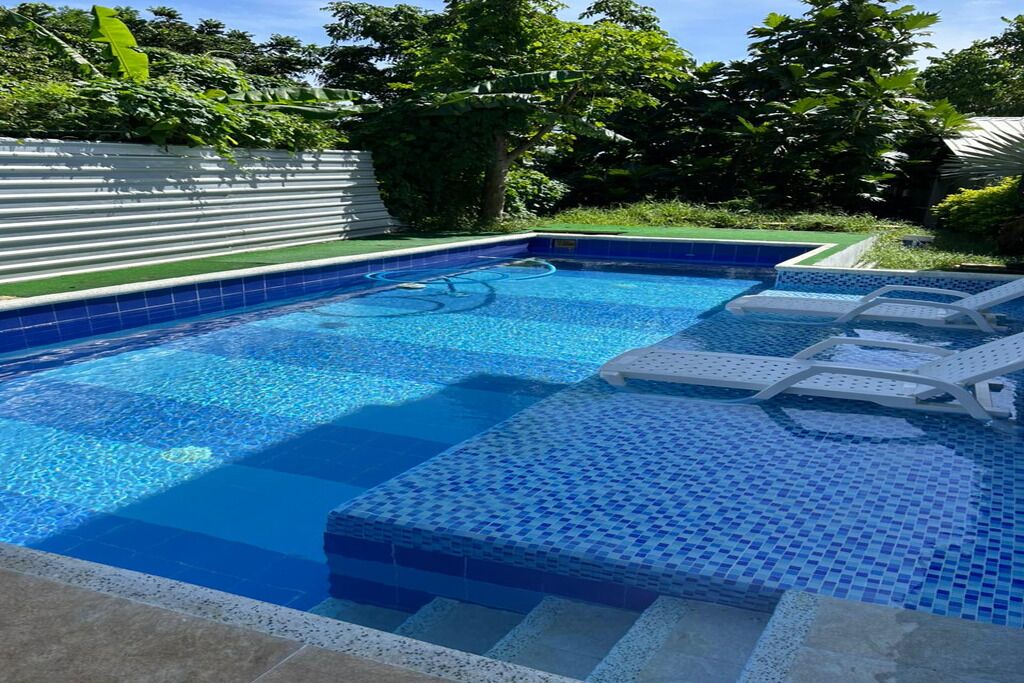 Una piscina rectangular con azulejos azules y una pequeña cascada.