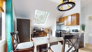 A modern kitchen with wooden cabinets, a dining area with a table and chairs, and a skylight above the kitchen.