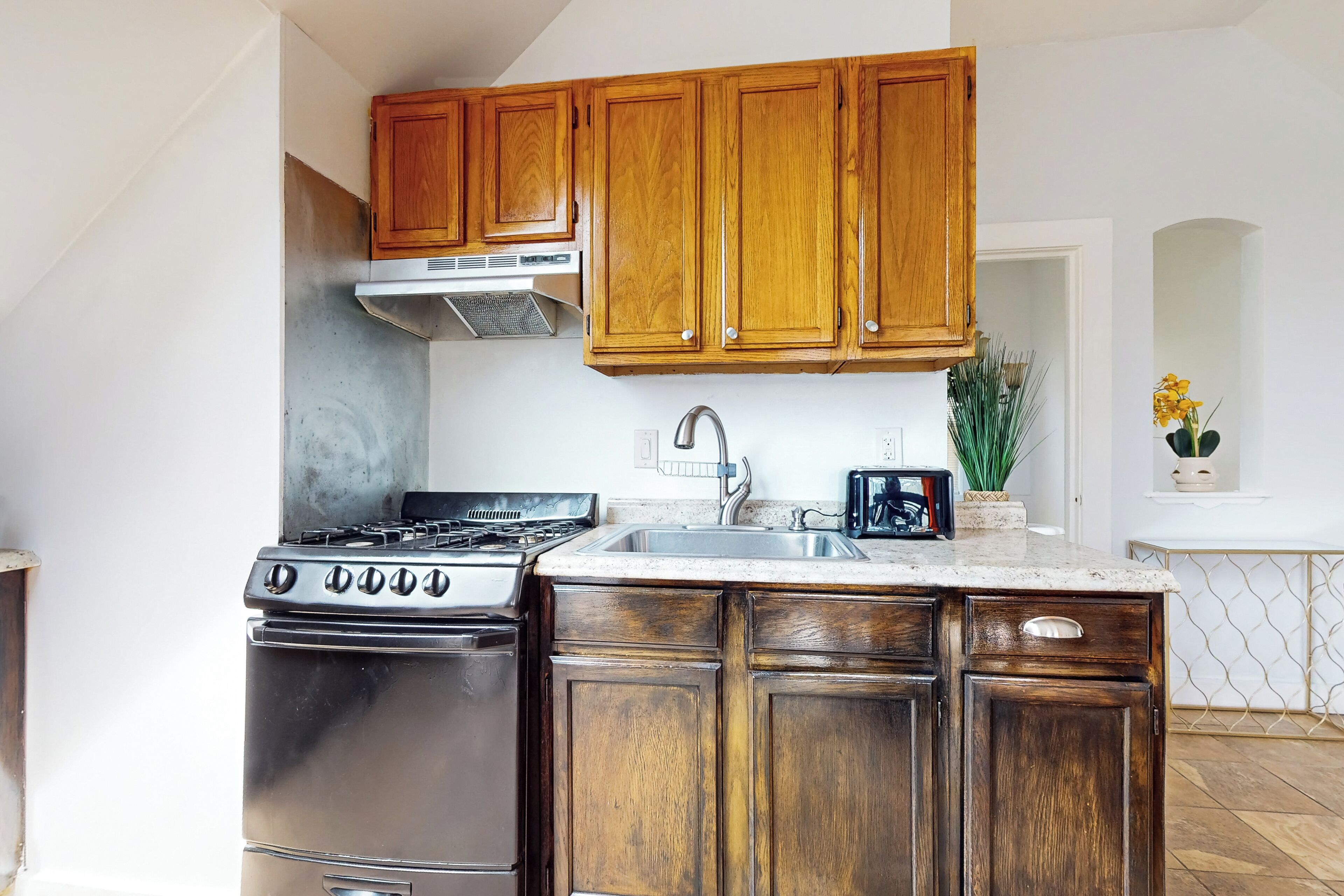 A kitchen with wooden cabinets, a stainless steel stove, and a sink.