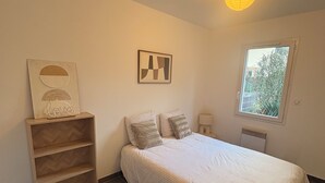A bedroom with a bed, a nightstand, a lamp, a window, and a wall with a framed picture. - House near Bordeaux, 3 minutes from the ARENA (Bouliac)