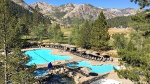 A resort with a large pool, lounge chairs, and a mountainous backdrop.