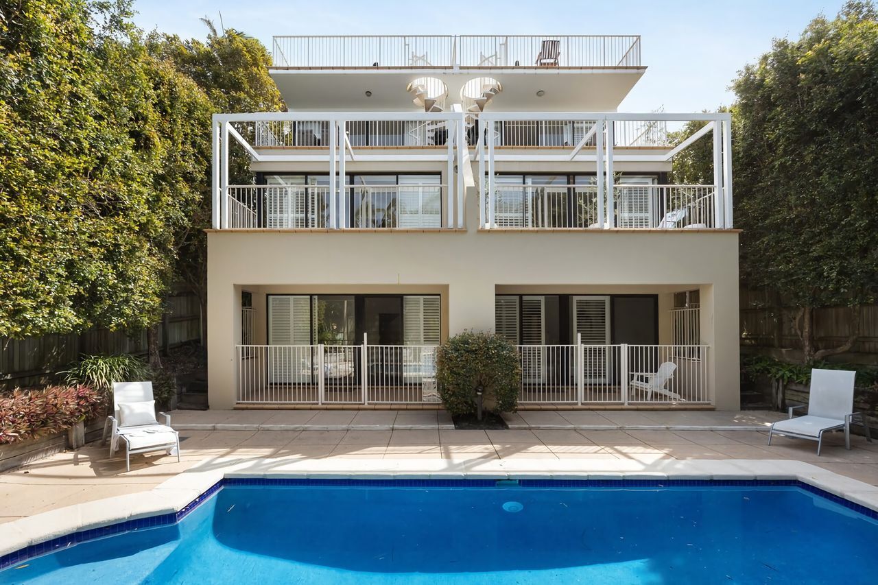 Ein zweistöckiges Wohnhaus mit Schwimmbad, Balkonen und einem eingezäunten Patio.