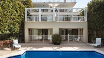 Ein zweistöckiges Wohnhaus mit Schwimmbad, Balkonen und einem eingezäunten Patio.