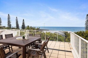 A wooden table with chairs on a balcony overlooking the sea. - Breezy Beach Haven - Ocean Views & Roof Top Deck (Sunshine Beach)