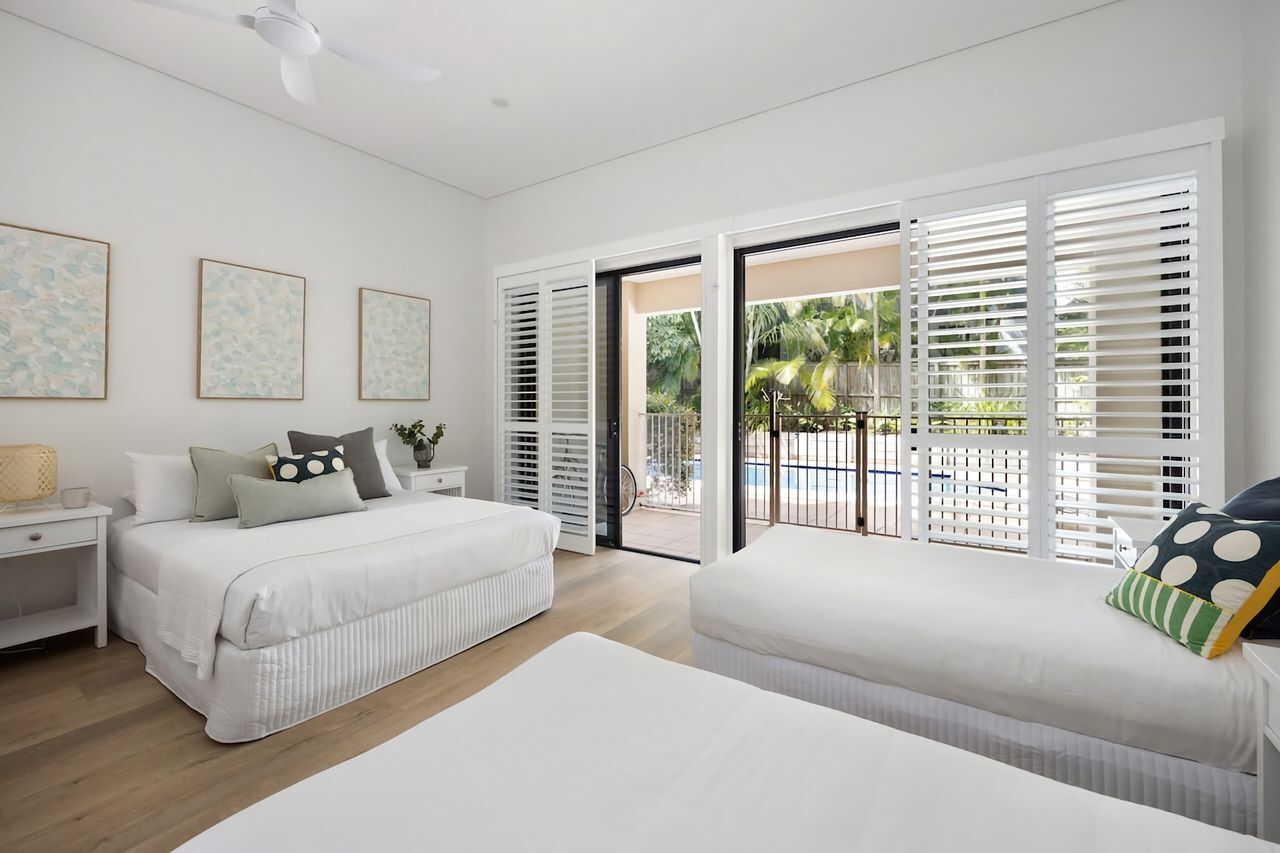 A bedroom with a bed, bedside tables, and a view of the outside.
