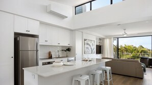 Una cocina moderna con armarios blancos, un refrigerador de acero inoxidable y una isla grande con taburetes.