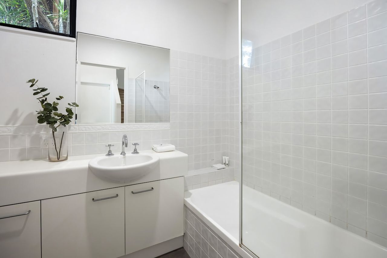 Een moderne badkamer met een wit wastafelmeubel, spiegel en bad.