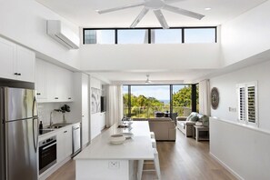 A modern kitchen with a central island, stainless steel appliances, and a dining area with a view.