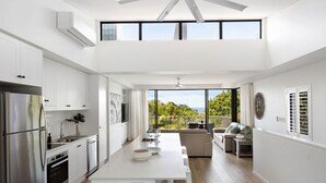 Una cocina moderna con armarios blancos, un refrigerador de acero inoxidable y un comedor con mesa y sillas blancas.